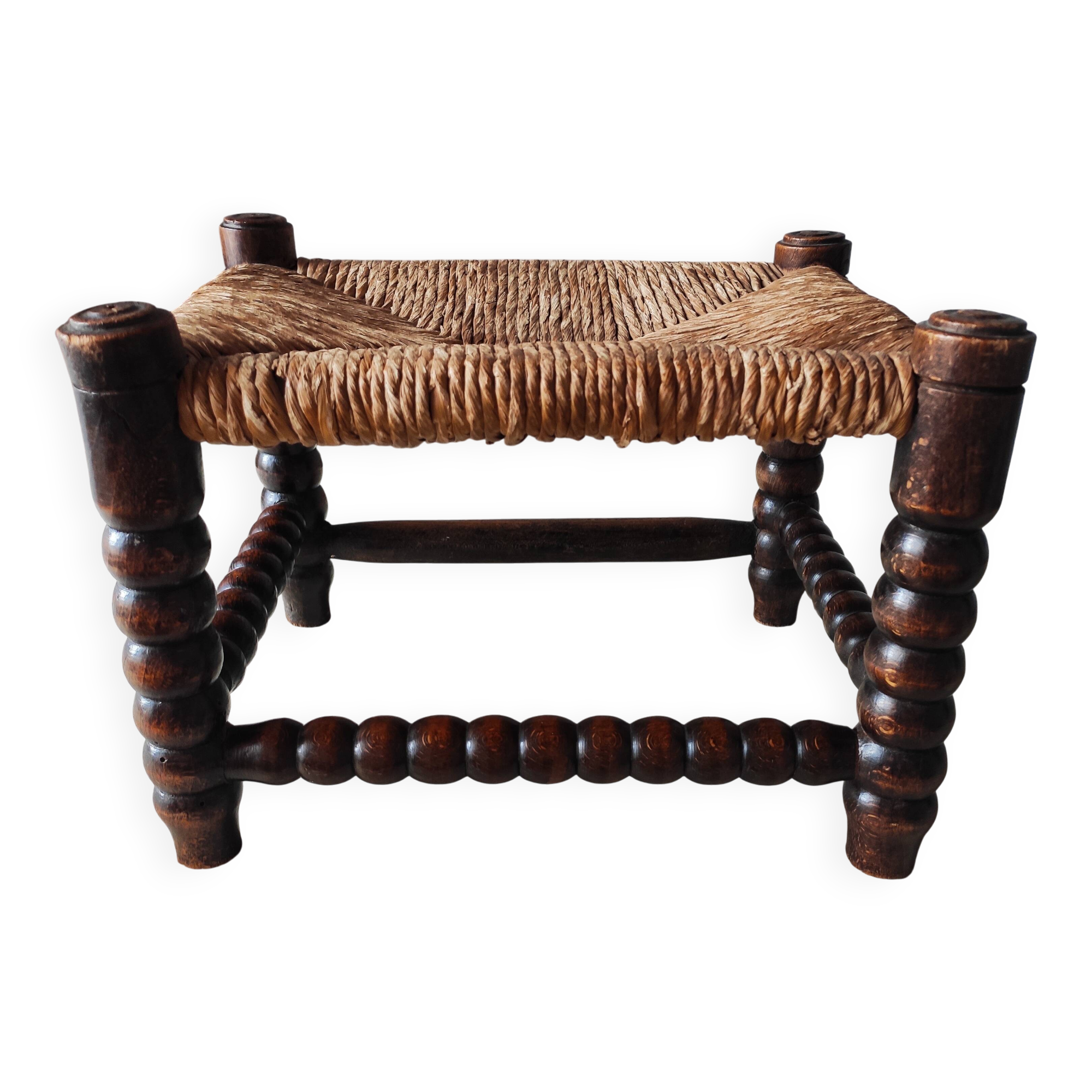 Antique wooden turned spool footrest with straw.
