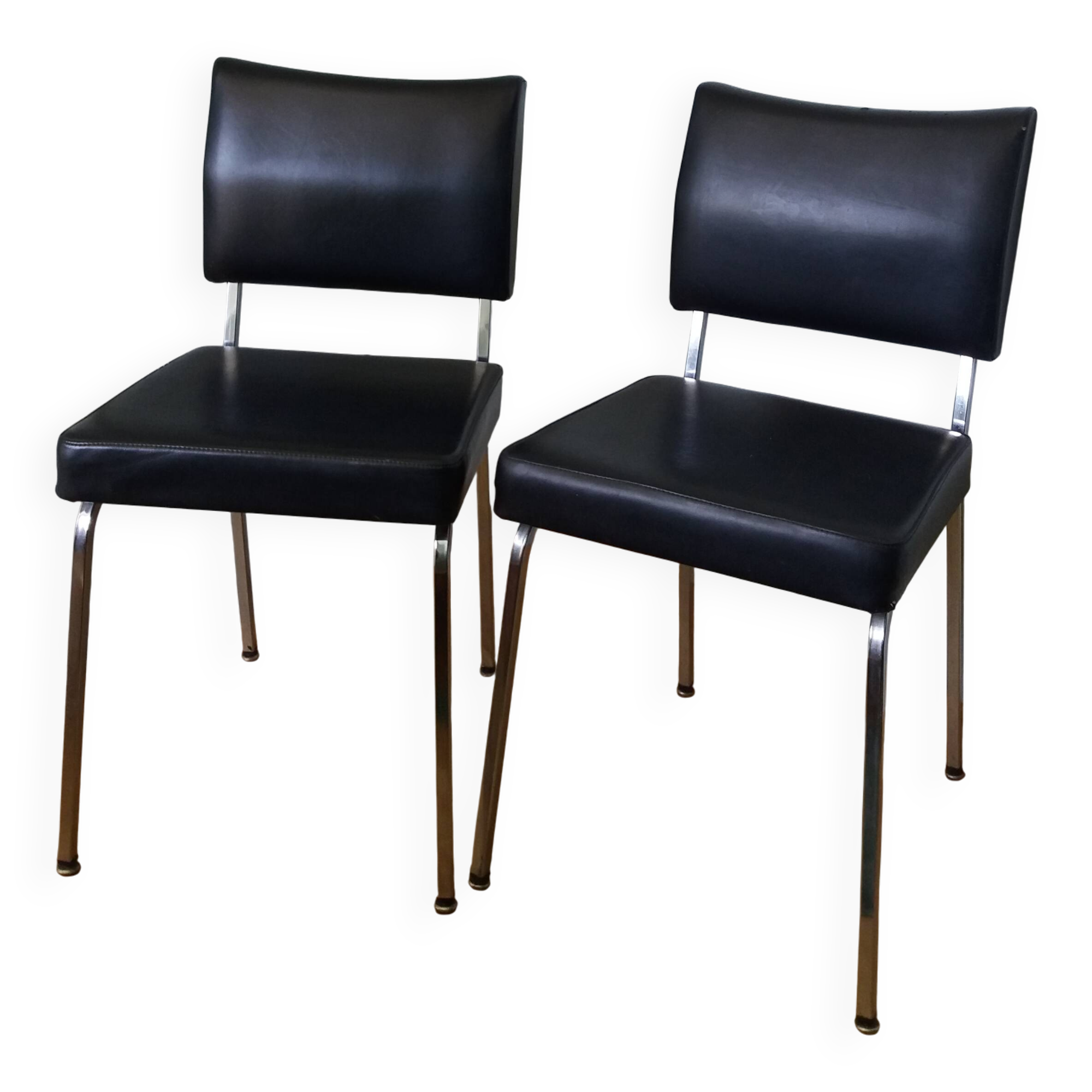 Chrome metal chairs and black faux leather upholstery in retro modernist style.