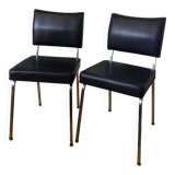 Chrome metal chairs and black faux leather upholstery in retro modernist style.