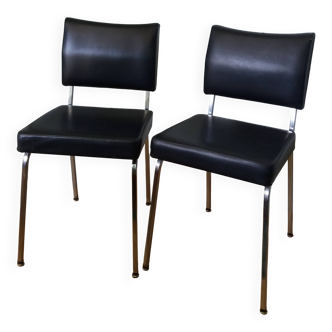 Chrome metal chairs and black faux leather upholstery in retro modernist style.