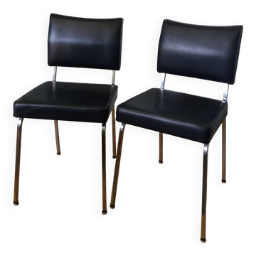 Chrome metal chairs and black faux leather upholstery in retro modernist style.