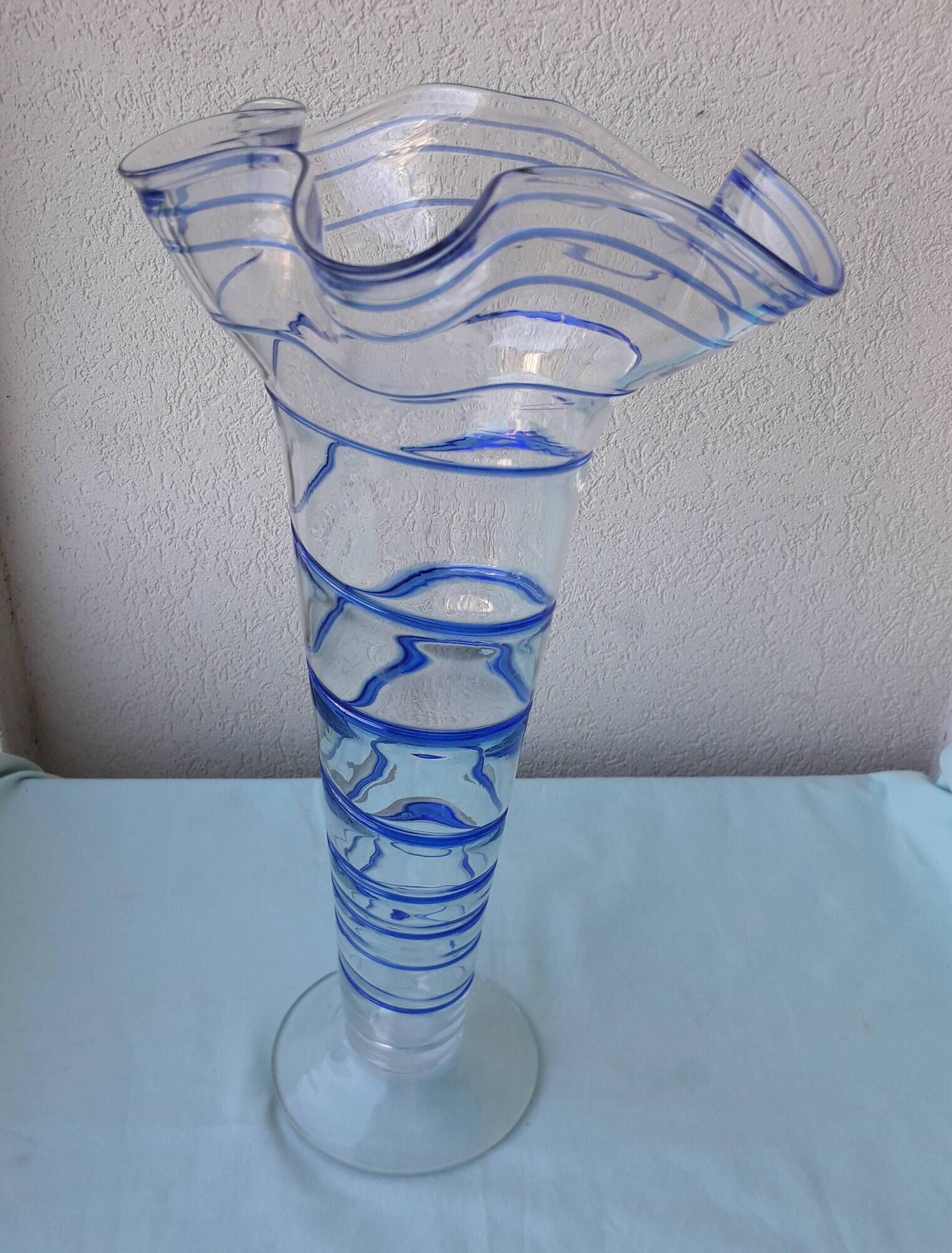 Glass vase on a pedestal with a blue trim.
