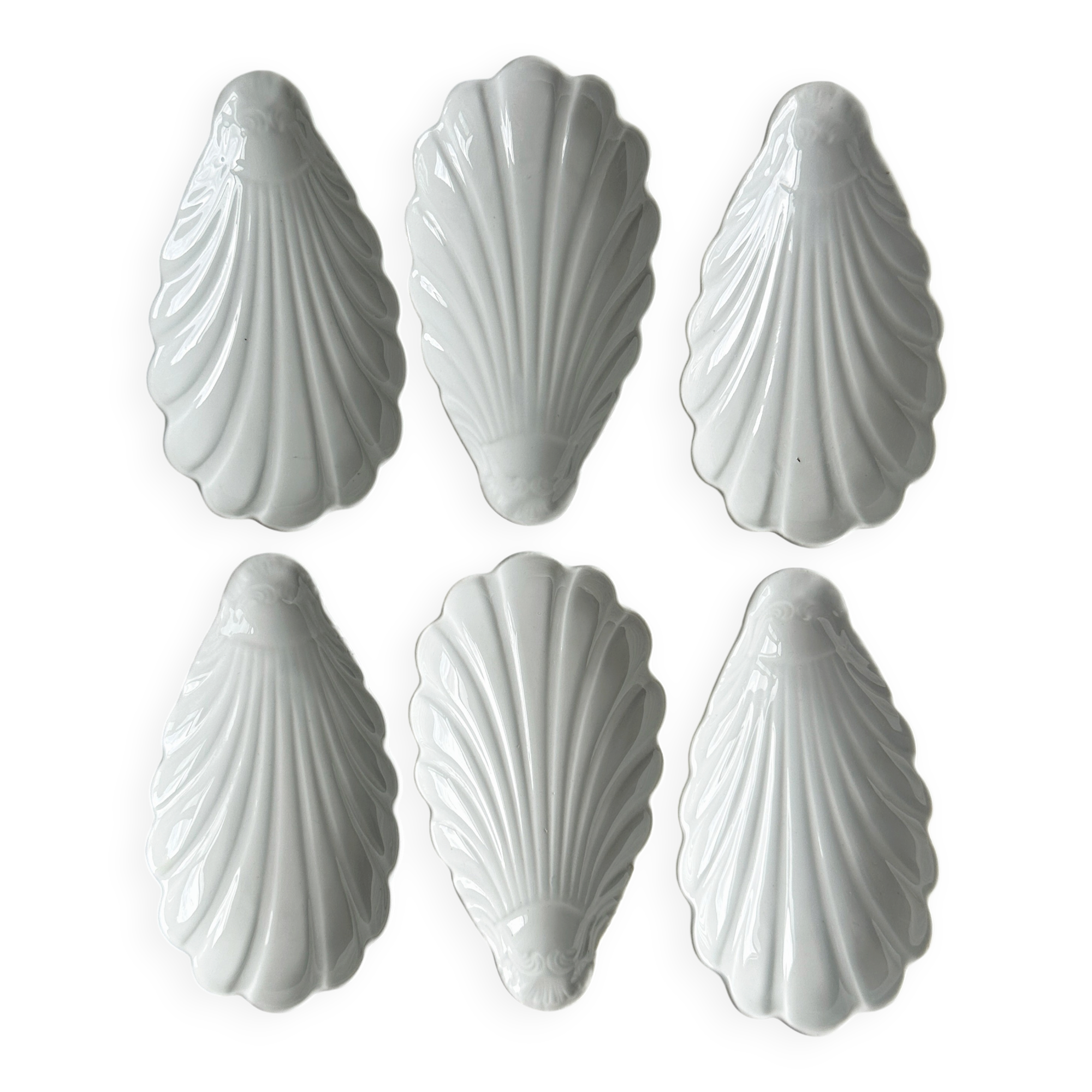Set of white porcelain ramekins, ribbed shell shape.