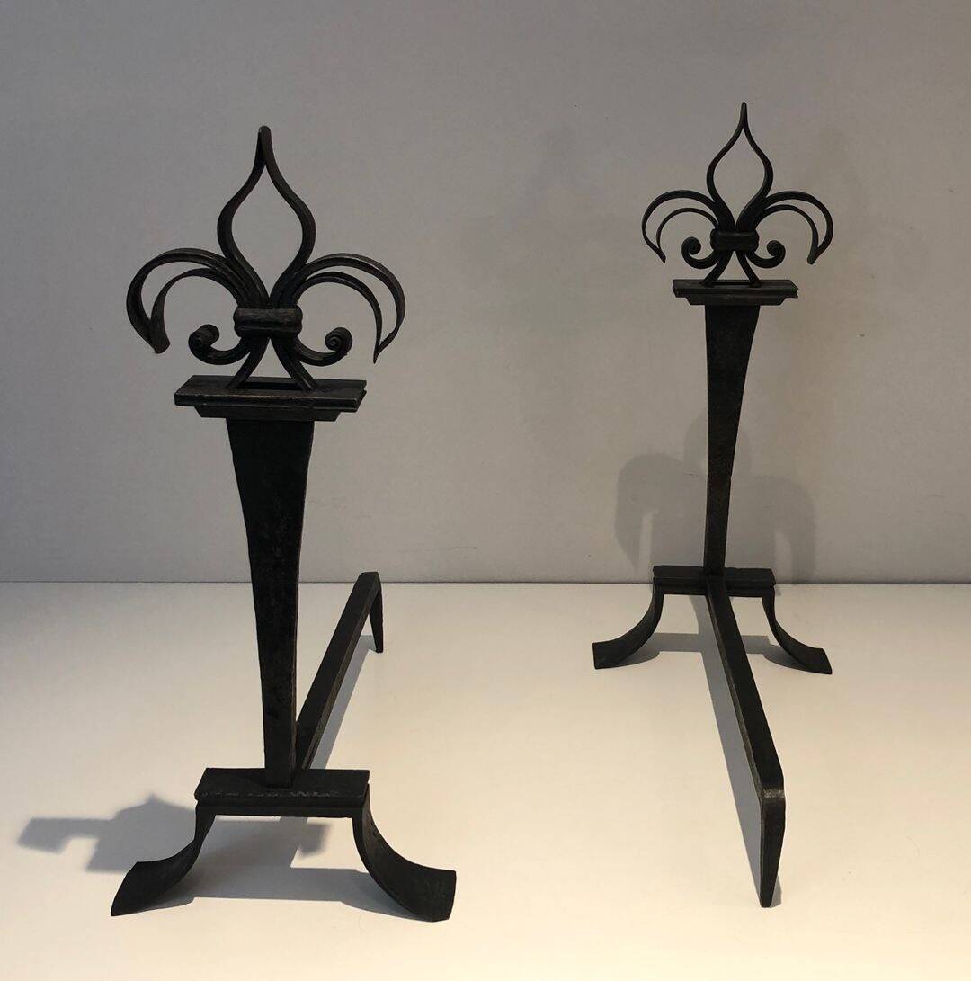 Important pair of wrought iron andirons with torch in heraldic fleur-de-lis design.