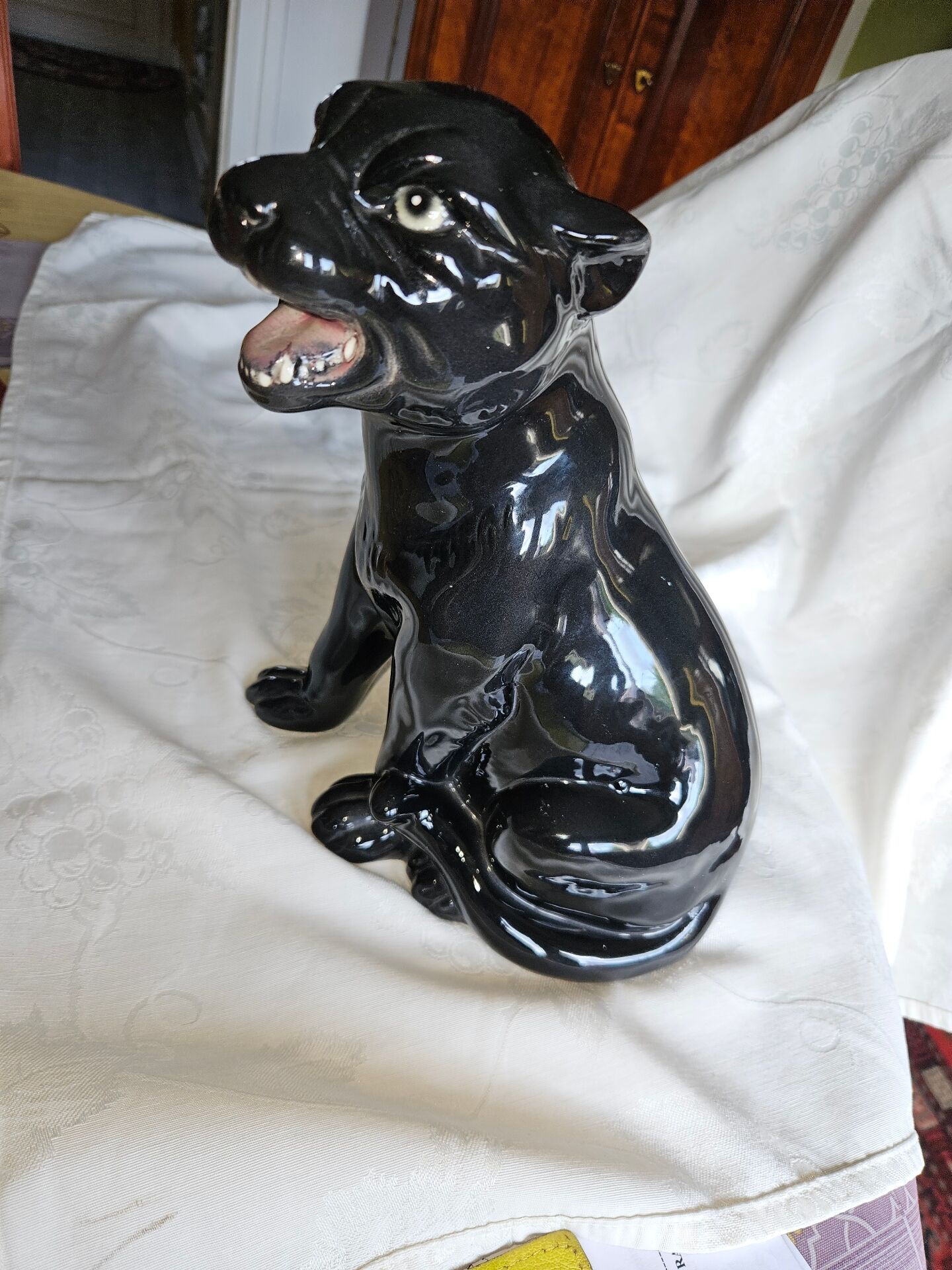Statue of a roaring panther/leopard sitting in black glazed ceramic.