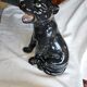 Statue of a roaring panther/leopard sitting in black glazed ceramic.