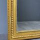Large antique gilded wooden mirror in Louis XVI style with a sculpted pediment, 19th century.