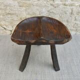 Tripod stool made of solid wood, with a carved seat.