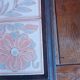 Ceramic tile trivet with floral patterns in pastel tones.