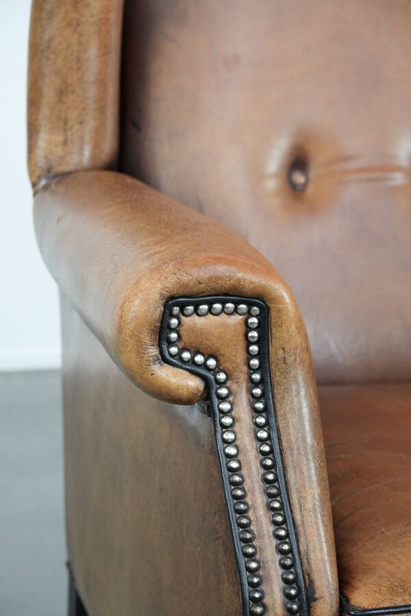 Grand et confortable fauteuil en cuir de mouton avec des passepoils noirs.