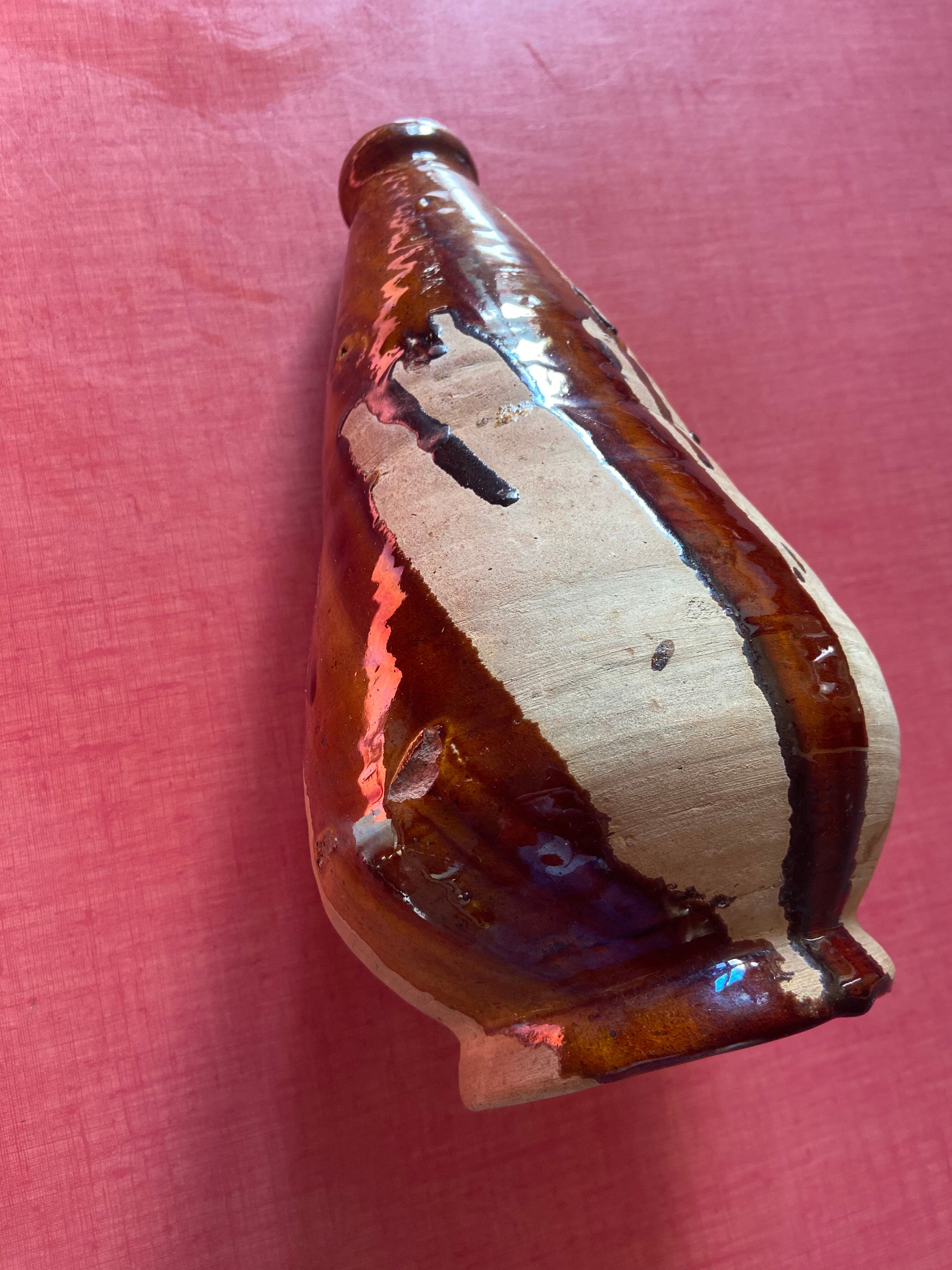 Large antique pottery bottle in glazed terracotta with drips.