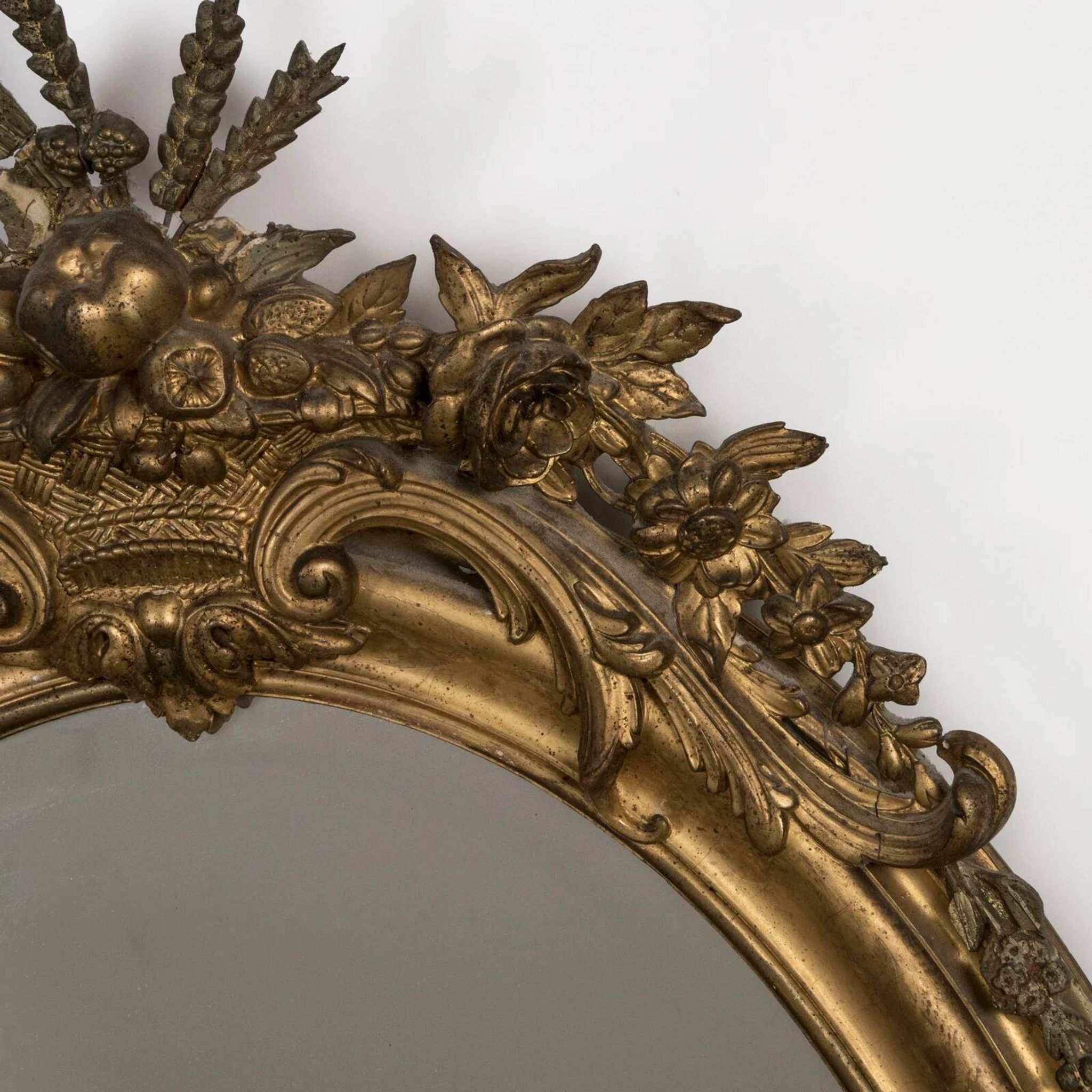 French 19th-century oval mirror in gold leaf with a pediment.