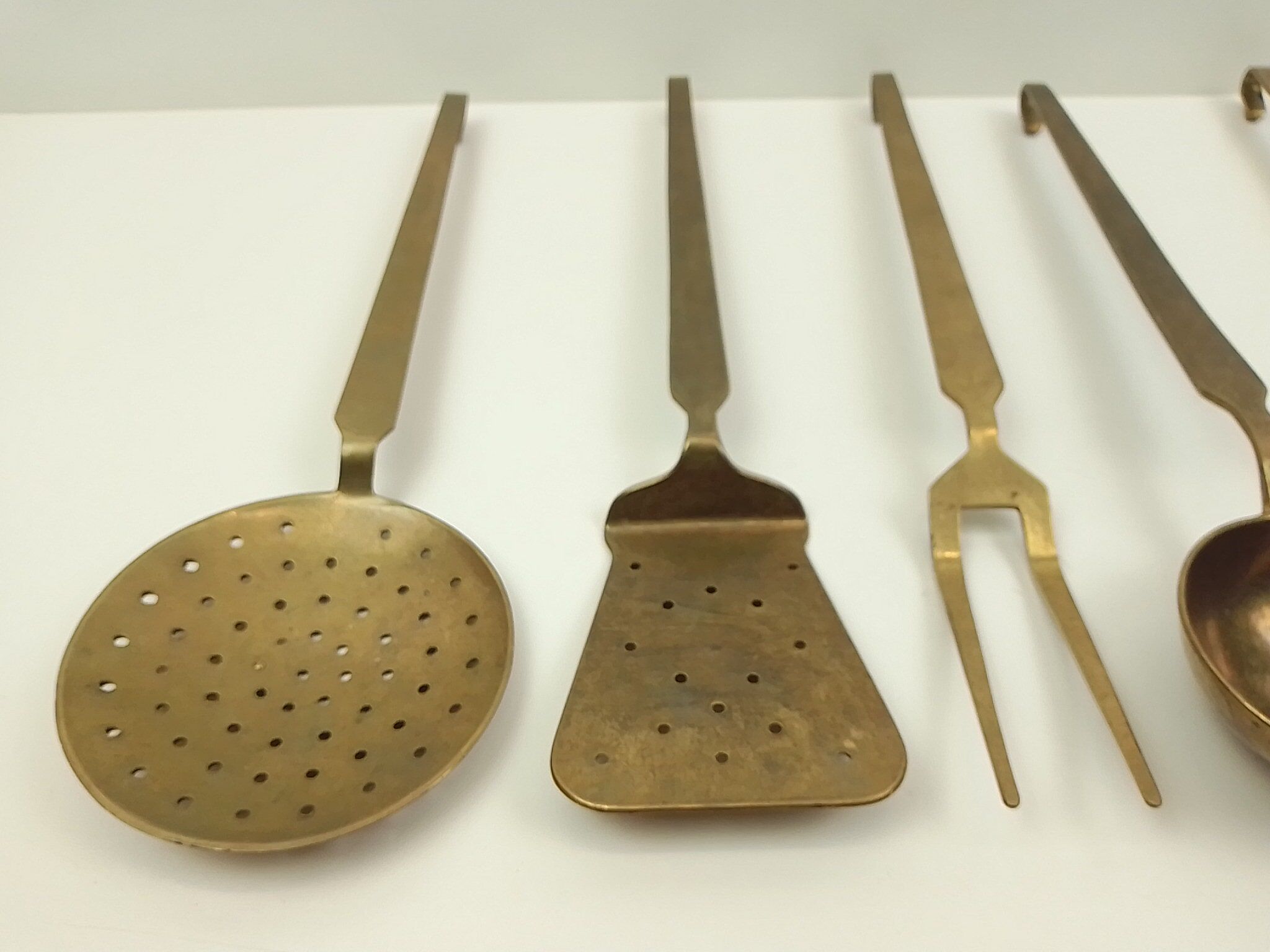 5 kitchen utensils and a brass wall mount