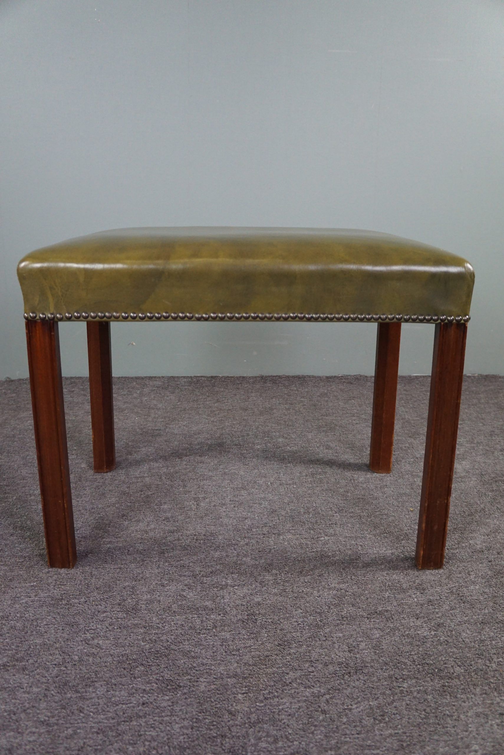 Elegant armchair and footrest in English green leather