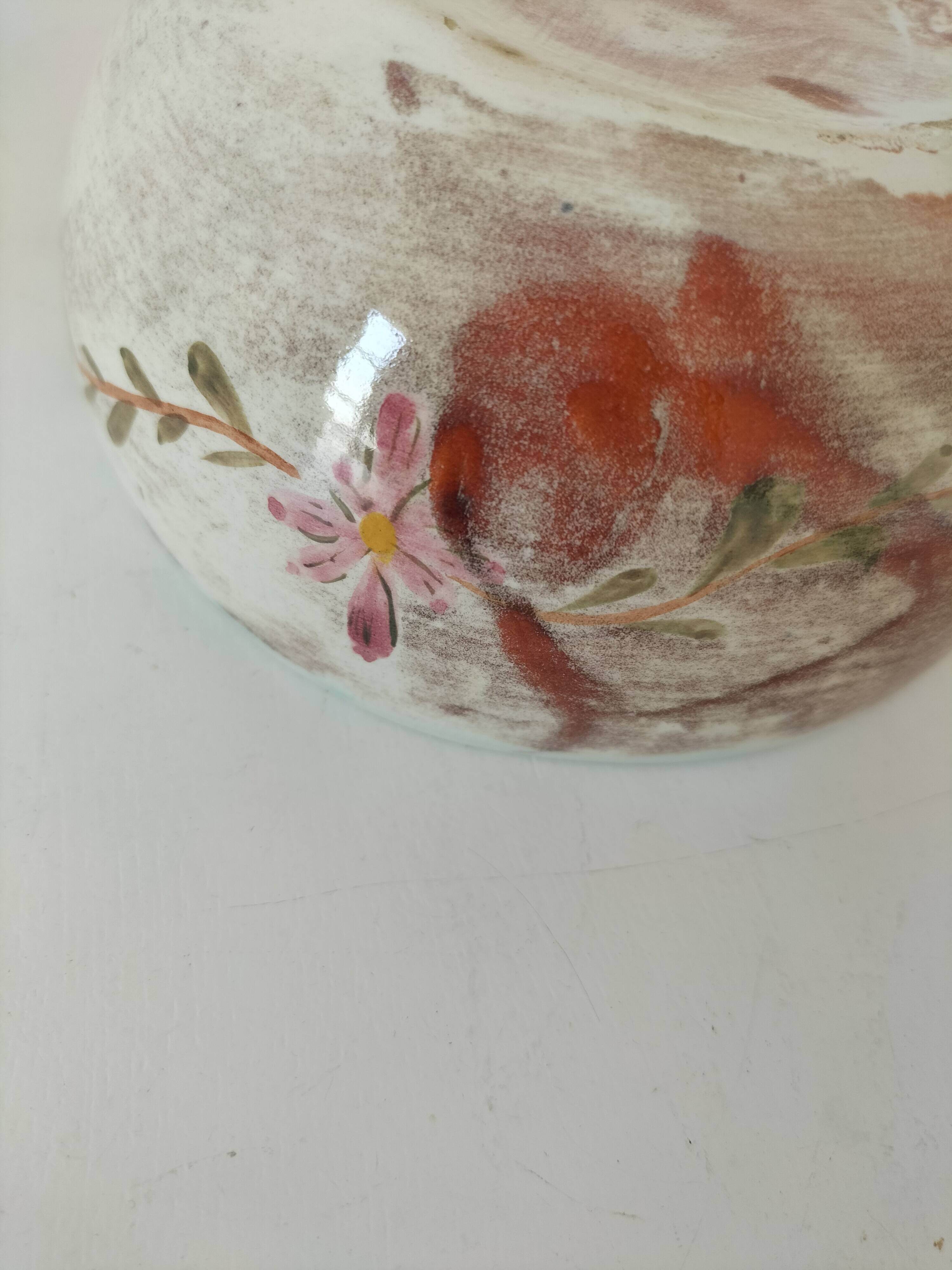 Red-orange glazed ceramic workshop bowl with floral decoration.