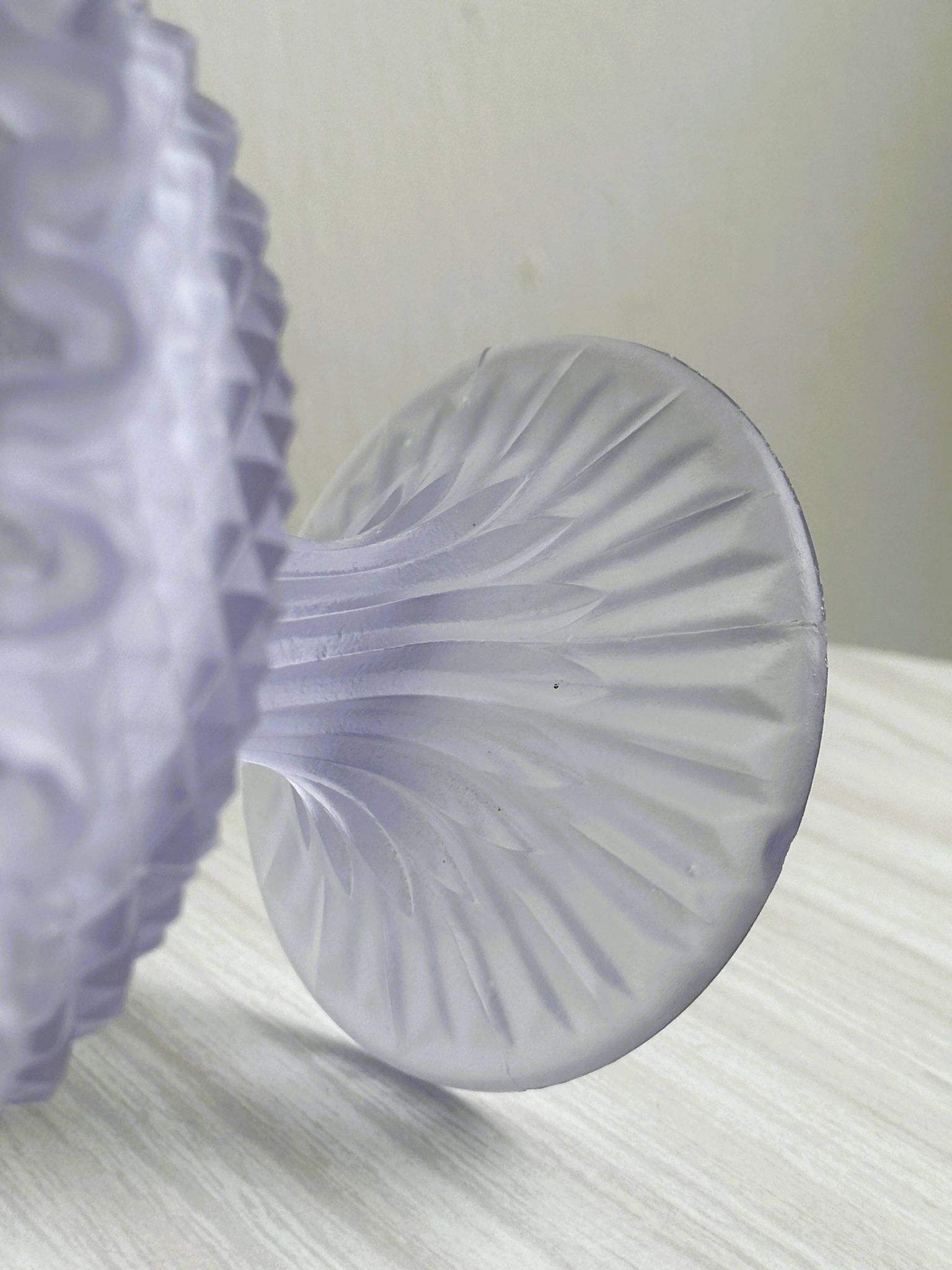 Purple glass pedestal bowl with wavy border and relief pattern.
