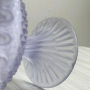 Purple glass pedestal bowl with wavy border and relief pattern.