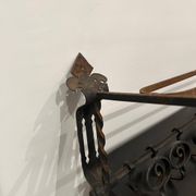 Large antique wall-mounted coat rack in wrought iron.