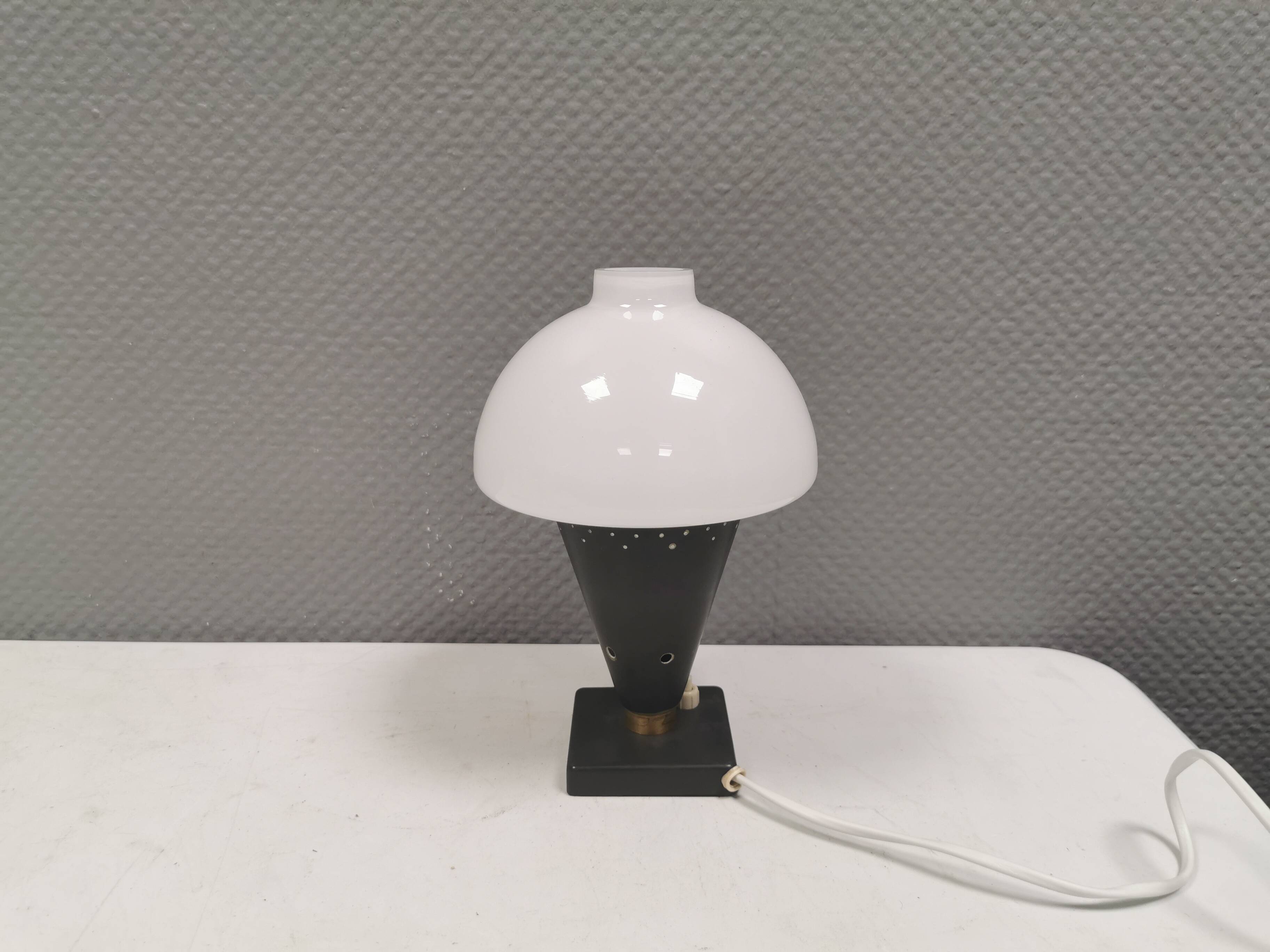 Small stylish table lamp with perforations and milky white opal glass shade