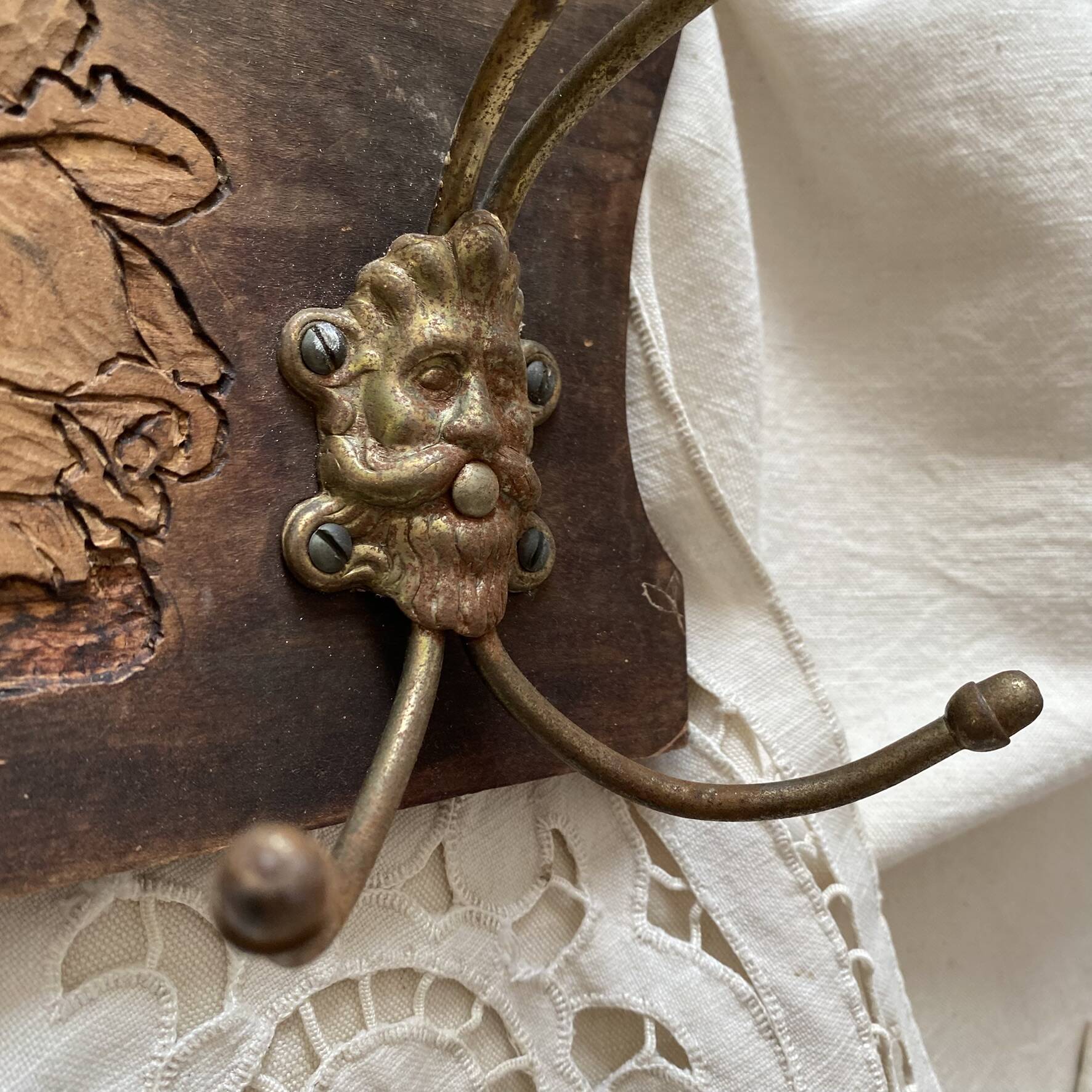 Wall-mounted coat rack in carved wood with rose decoration.