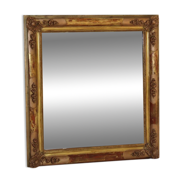 Miroir rectangulaire en bois doré à décor en relief de fleurs.