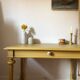 Desk table from the late 19th century, painted mustard, with turned stretcher.
