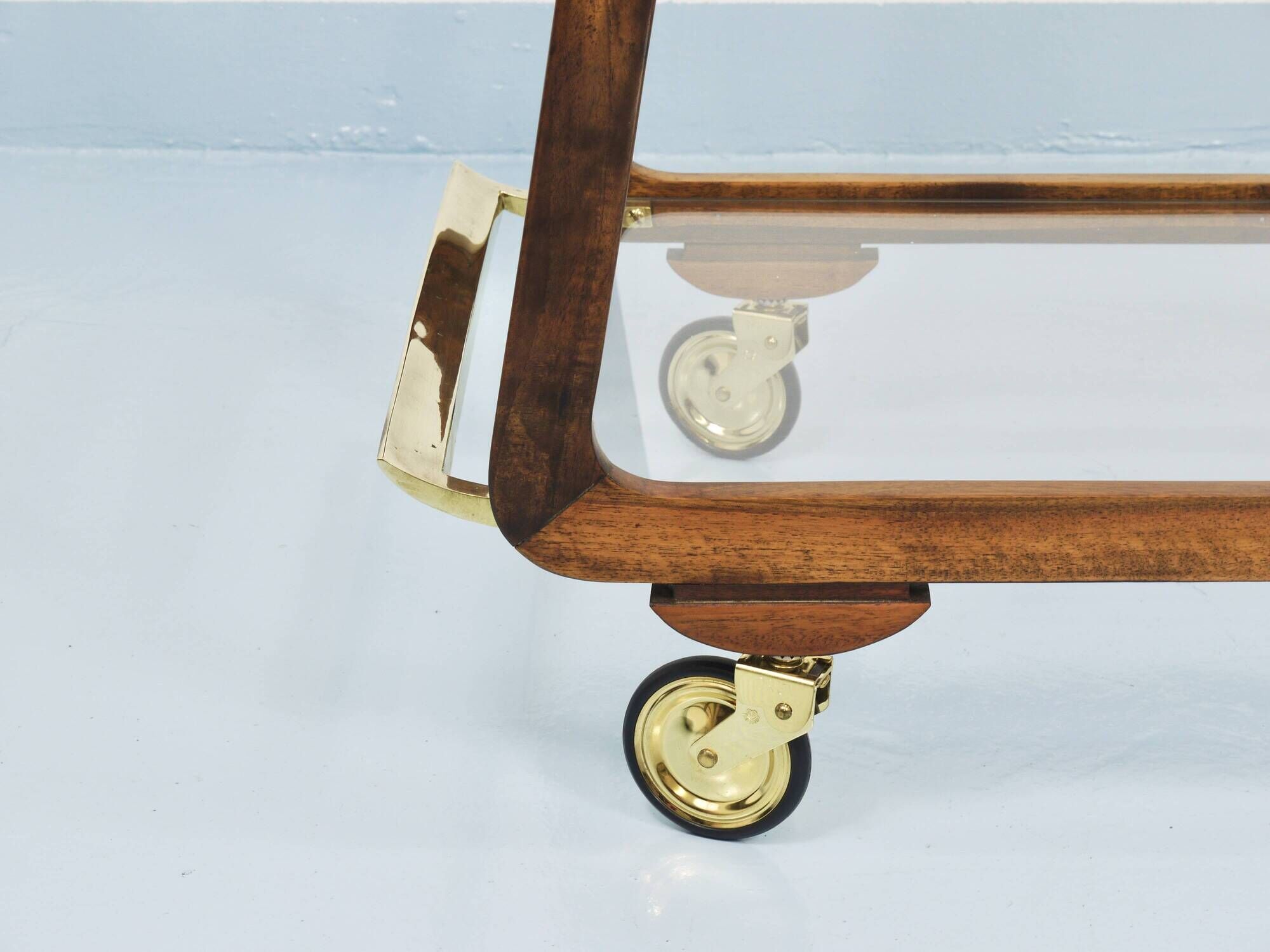 May include: A mid-century modern bar cart with a dark wood frame and two c
