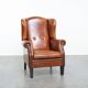 Large sheepskin wingback chair with black piping and decorative nails