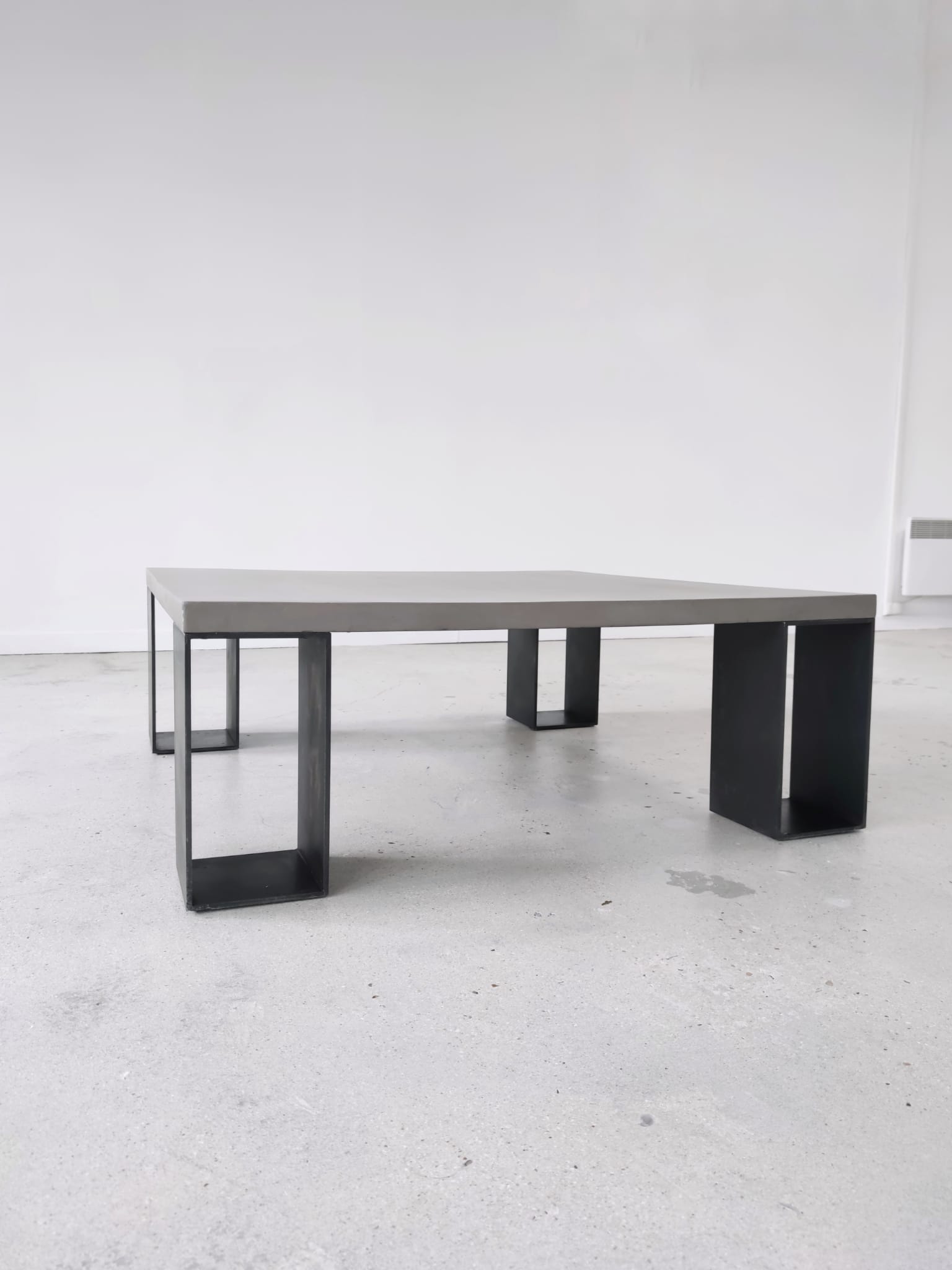 Table basse minimaliste en béton ciré et acier massif 1m20x1m20