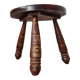 Small brutalist tripod stool made of turned wood.