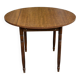 Round kitchen table with extendable leaves in dark wood.