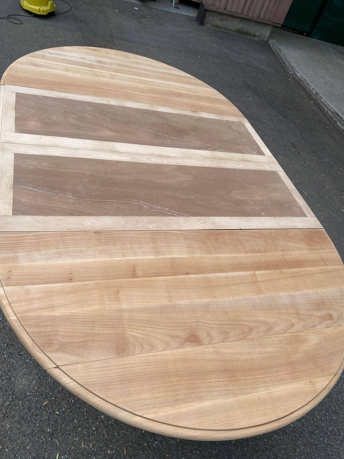 Round dining table with a central pedestal, extendable, stripped in solid walnut with 2 extensions.