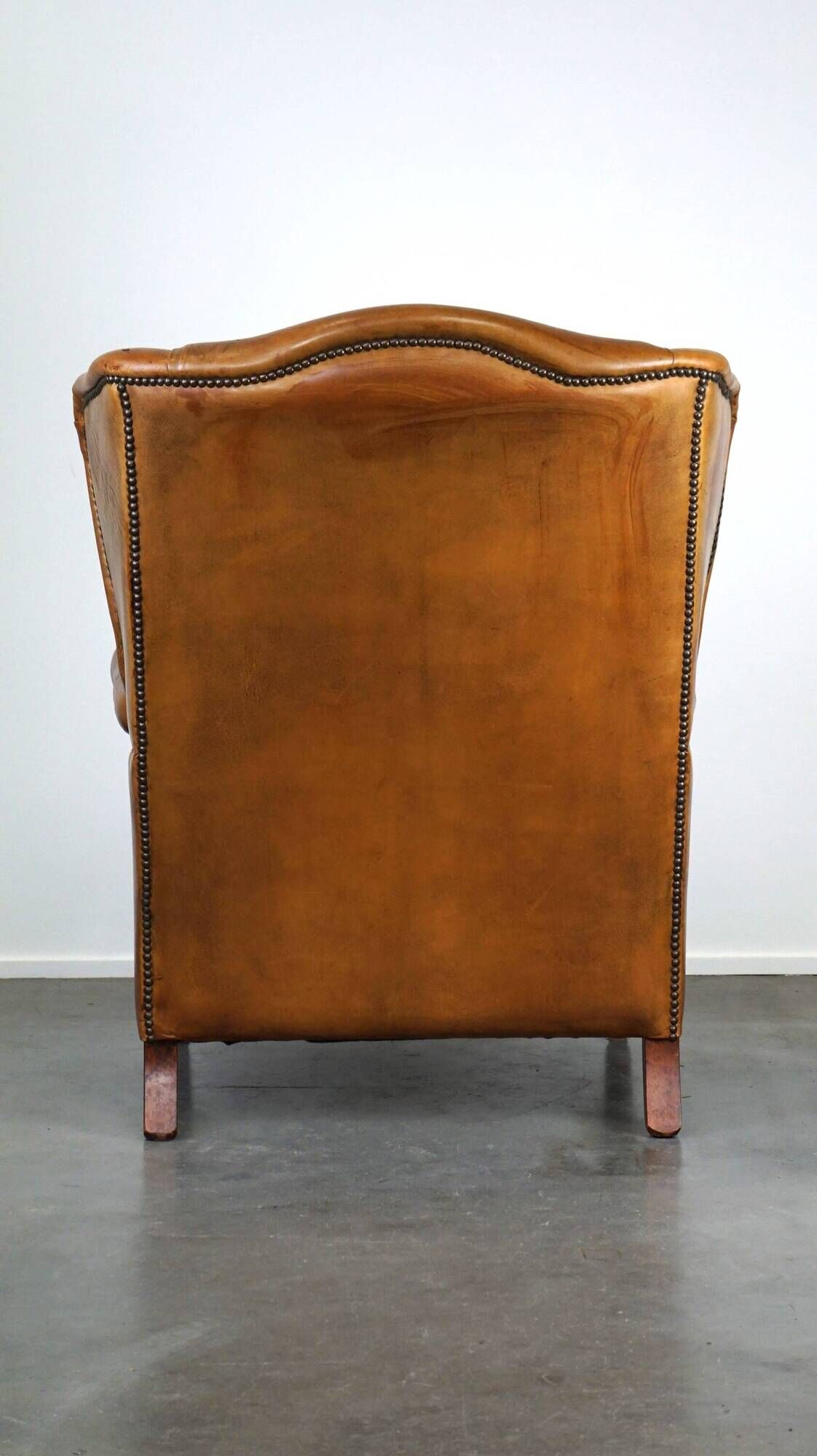 Positively lived-in sheepskin leather wing chair with pleasant seating comfort