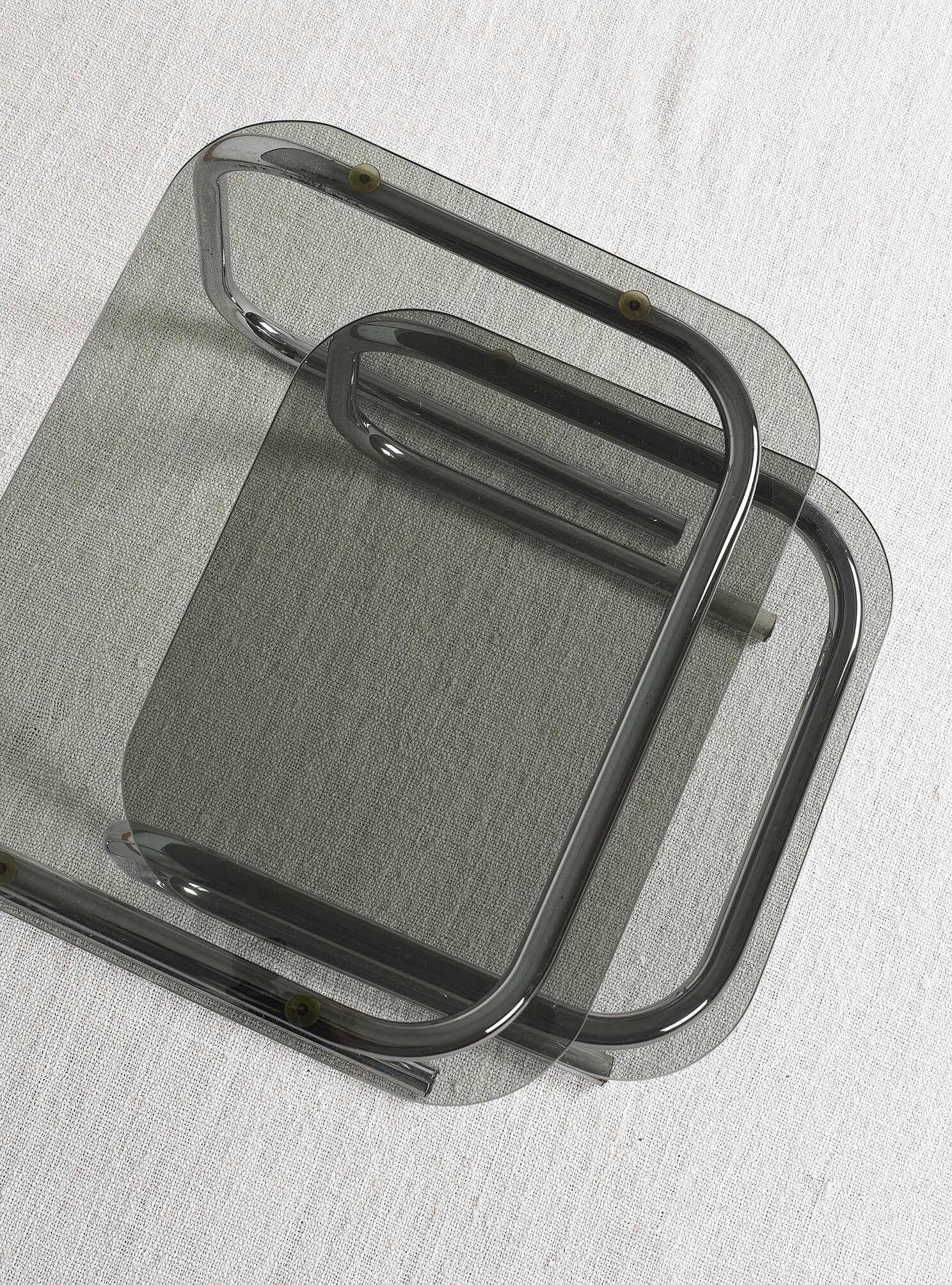 Pair of nesting tables in smoked glass and chrome legs.