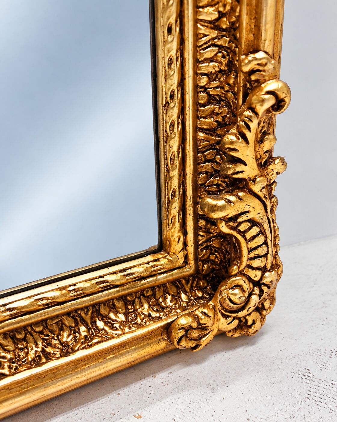 Grand miroir baroque en or avec un crête orné.