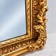 Grand miroir baroque en or avec un crête orné.