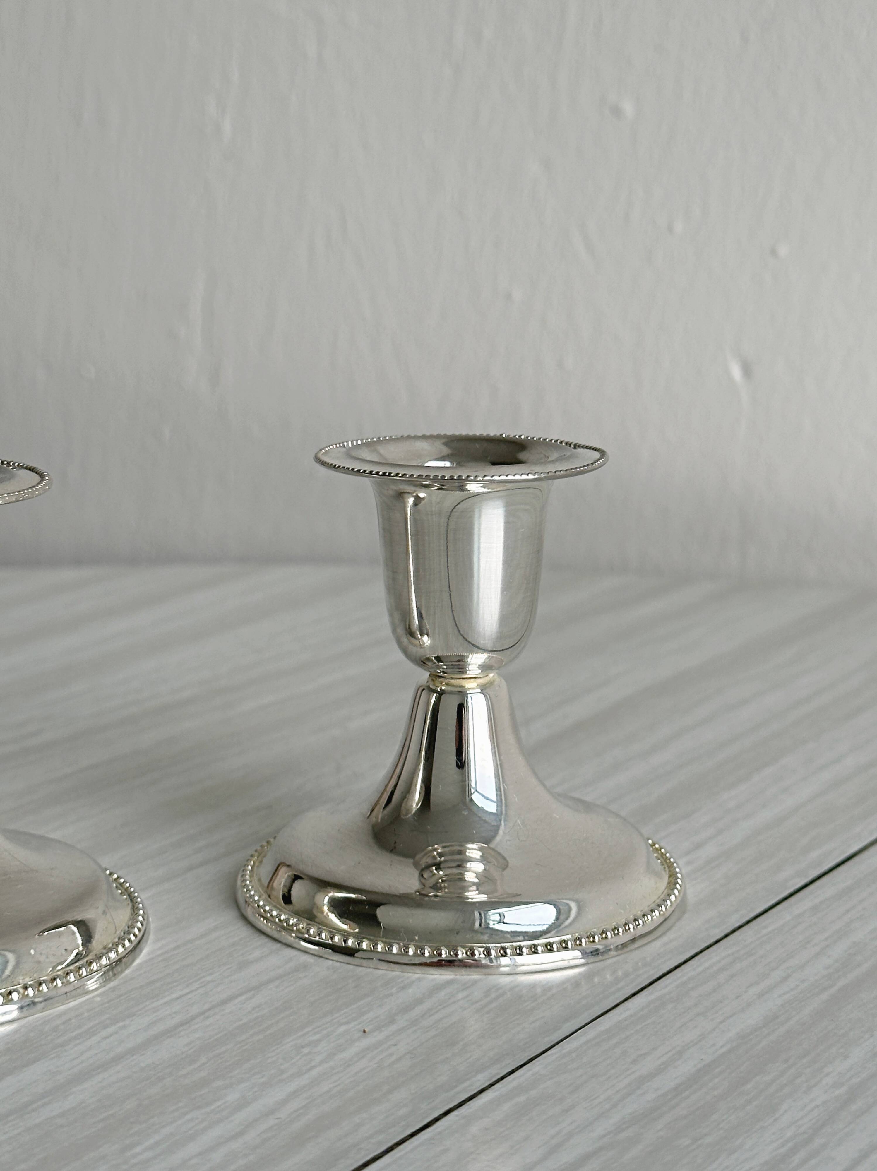 A pair of small silver-white metal candle holders.