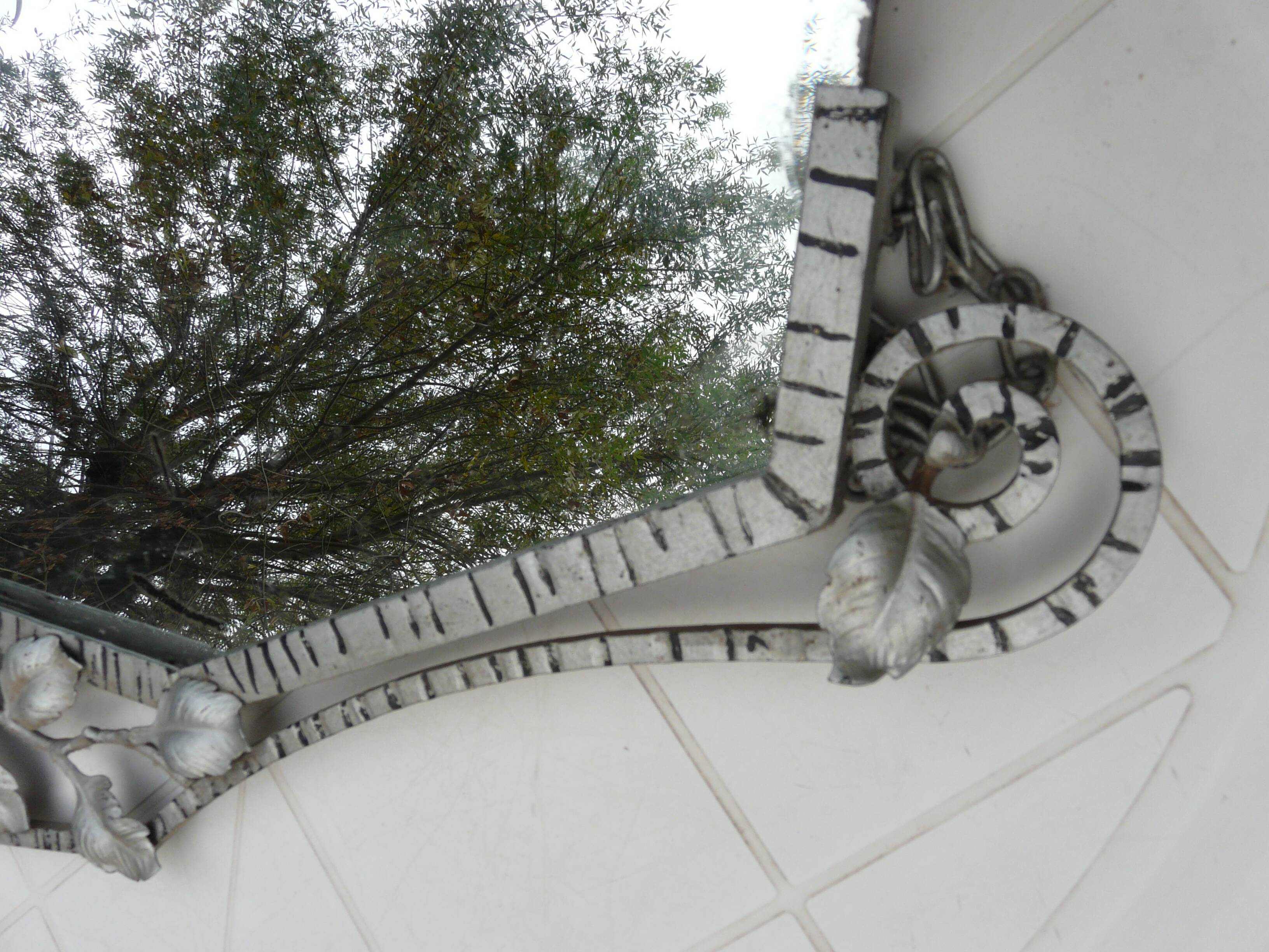 Beveled mirror with art-deco wrought iron frame and floral decor with hanging chain