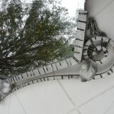 Beveled mirror with art-deco wrought iron frame and floral decor with hanging chain