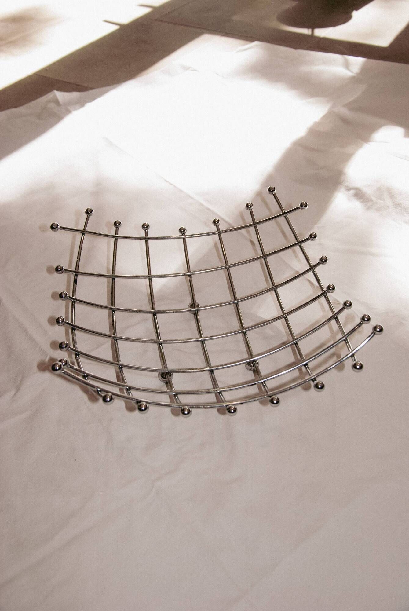 Curved grid fruit bowl, chrome metal and beads.