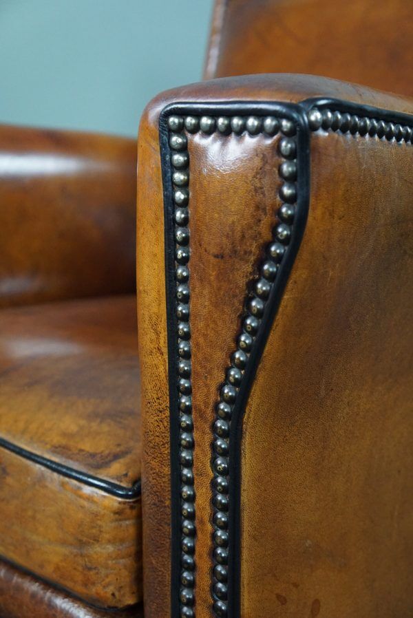 Art deco armchair in sheepskin with black piping and decorative nails