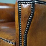 Art deco armchair in sheepskin with black piping and decorative nails