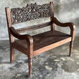 Small antique Indonesian bench in carved teak with plant and floral motifs.