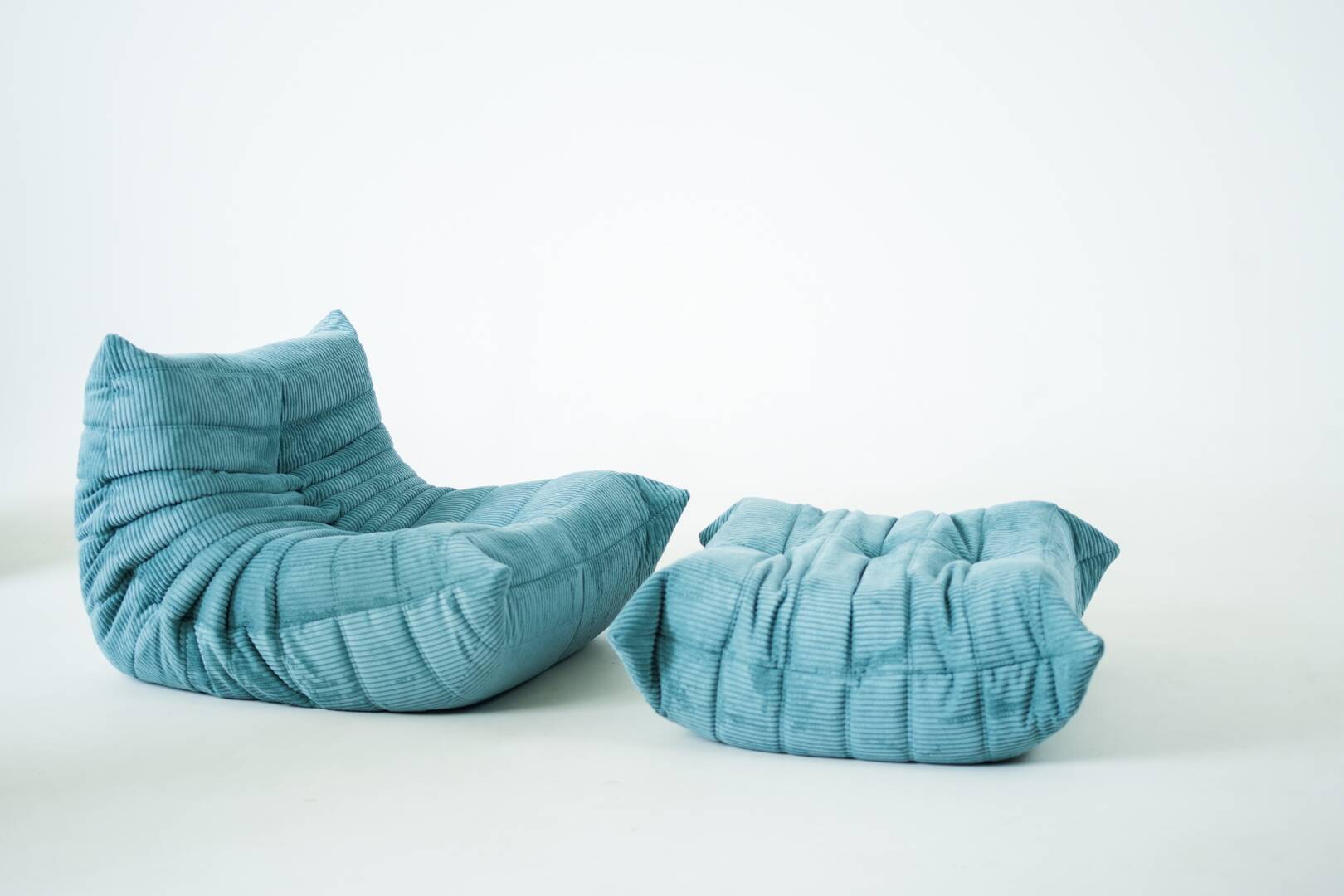 Ensemble de fauteuil et pouf Togo en velours côtelé bleu clair.
