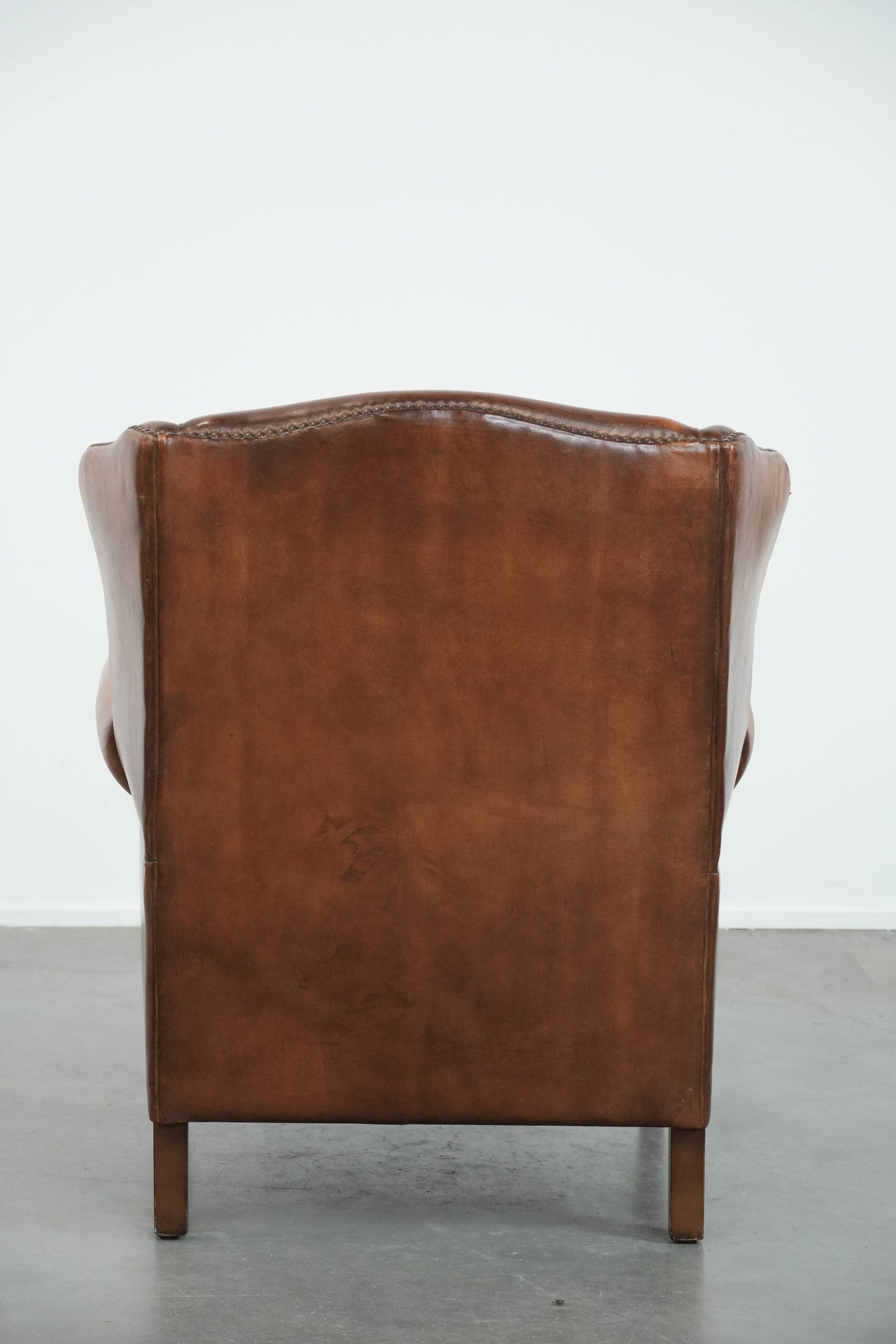 Fauteuil à oreilles en cuir de mouton charmant avec des couleurs chaudes.