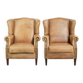 Ensemble de deux fauteuils à oreilles en cuir de vachette clair au style anglais intemporel.