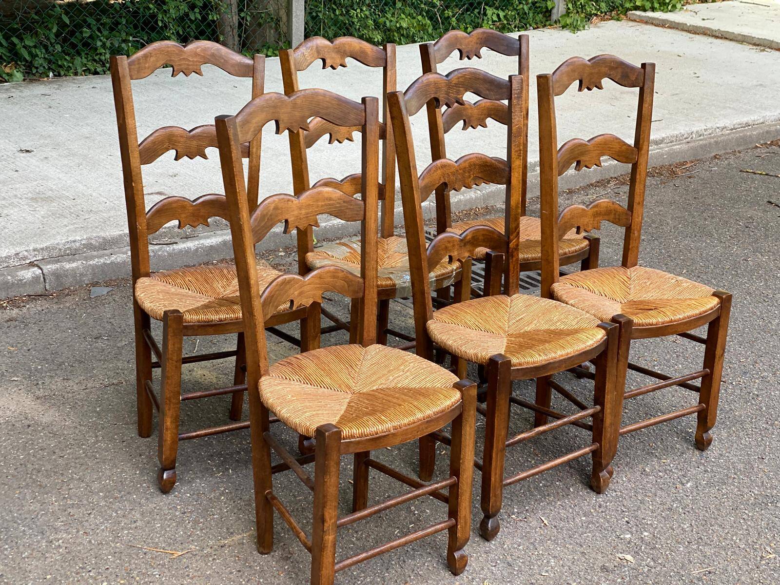 6 solid wood chairs with straw seats and butterfly carved backs.