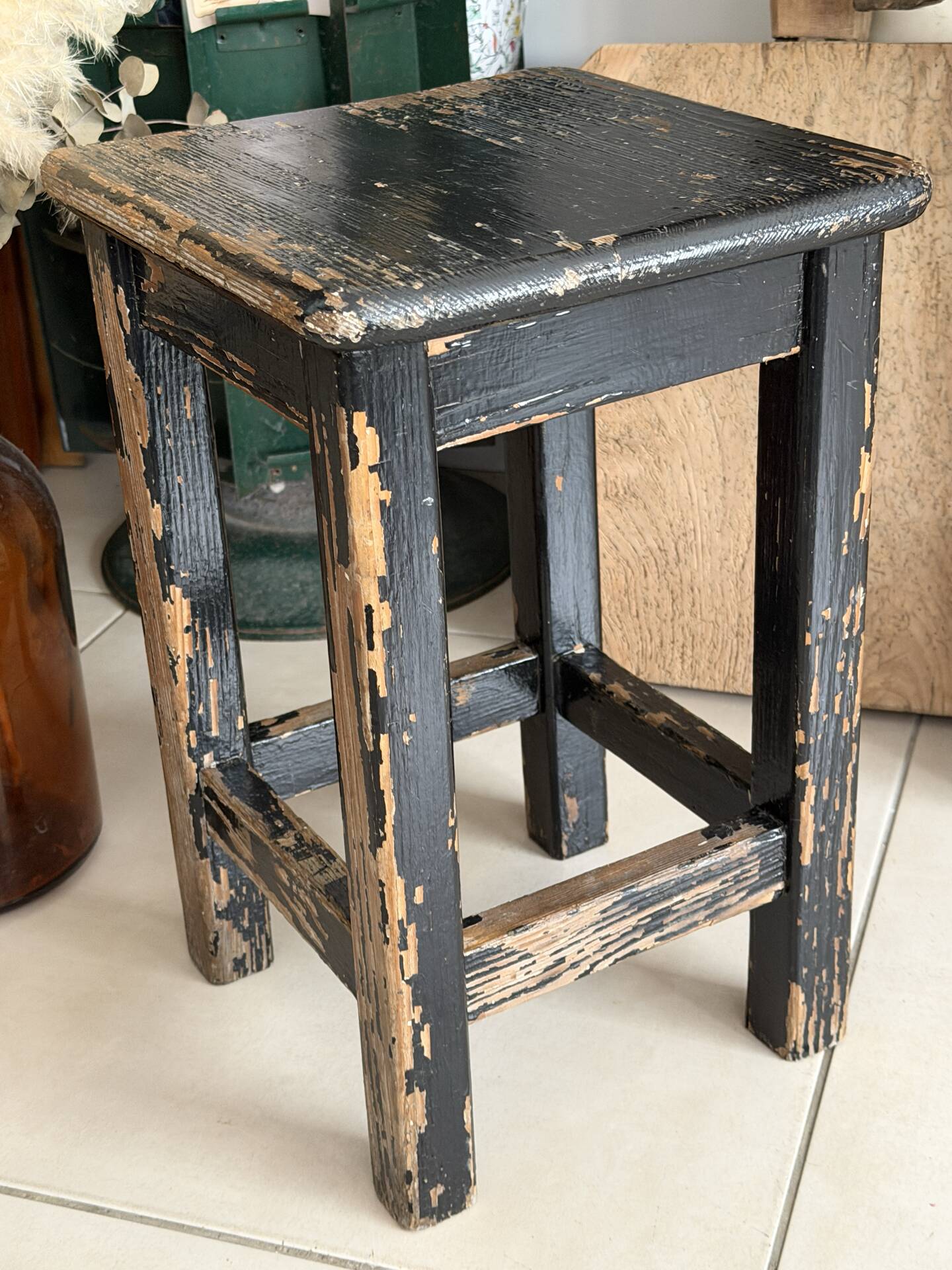 Solid wood stool with a worn black patina.