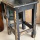 Solid wood stool with a worn black patina.