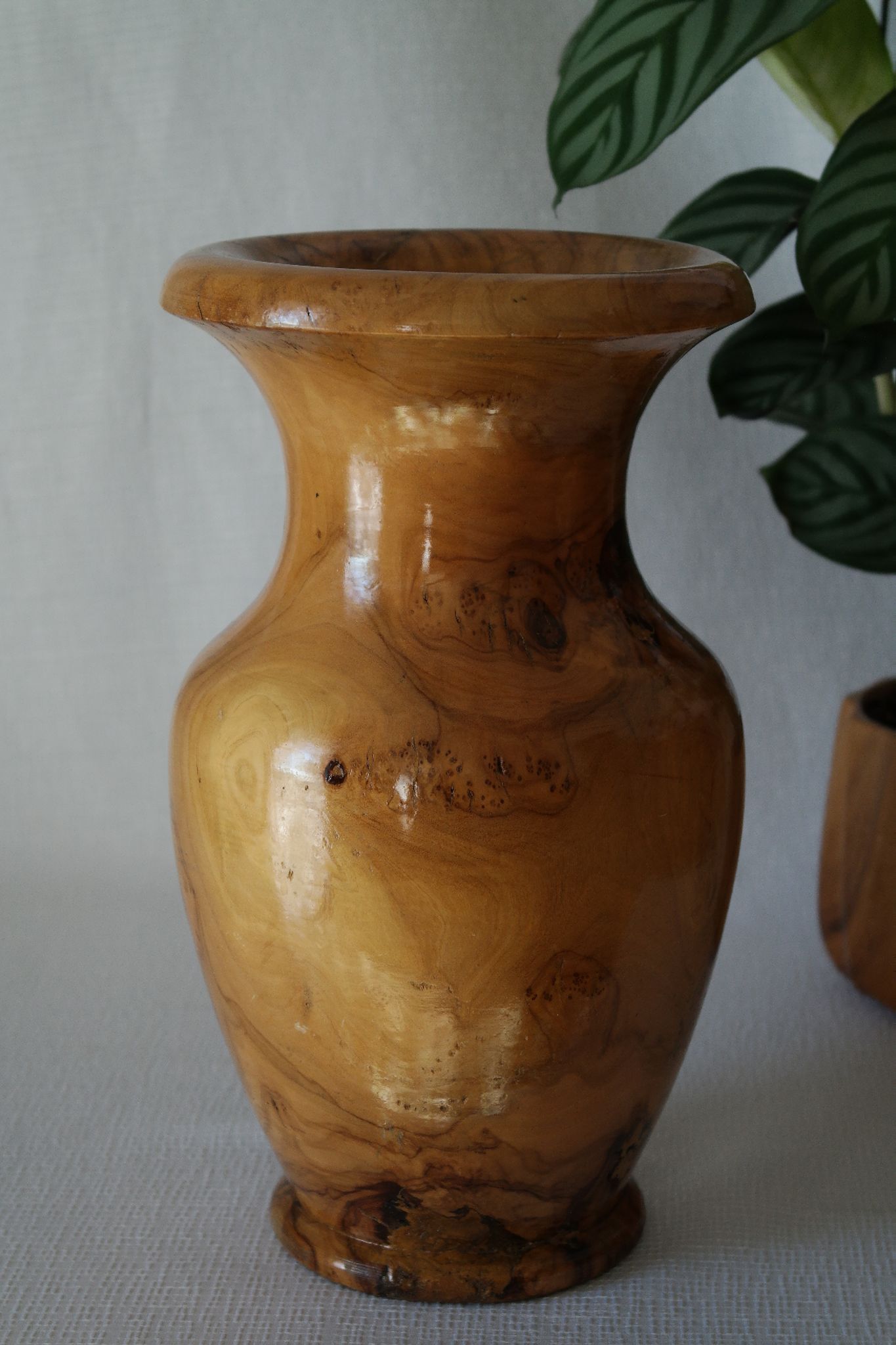 Artisanal turned olive wood vase with varnish.